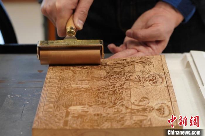 圖為徐晉林工作室工作人員正在給雕好壁畫的版面滾油墨?！【琶赖┰?　攝