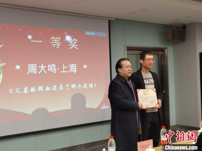 圖為作家、西北師范大學(xué)新聞與傳媒學(xué)院院長(zhǎng)徐兆壽頒發(fā)一等獎(jiǎng)證書(shū)，代領(lǐng)獎(jiǎng)?wù)呱吓_(tái)領(lǐng)獎(jiǎng)。　楊娜 攝