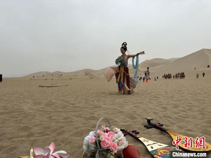 圖為2023年4月底，敦煌大漠“逐舞者”奧楠在鳴沙山月牙泉景區(qū)視頻直播敦煌舞?！●T志軍 攝