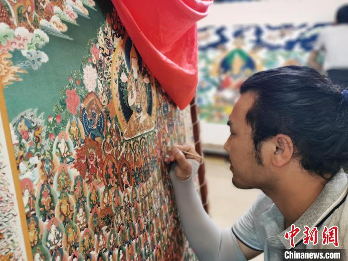 圖為更登才讓的徒弟繪畫唐卡?！?zhí)砀?攝