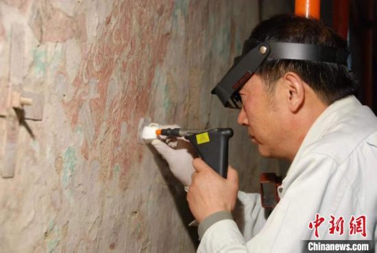 敦煌研究院研究員樊再軒進(jìn)行壁畫修復(fù)。(資料圖)張?jiān)莆?攝